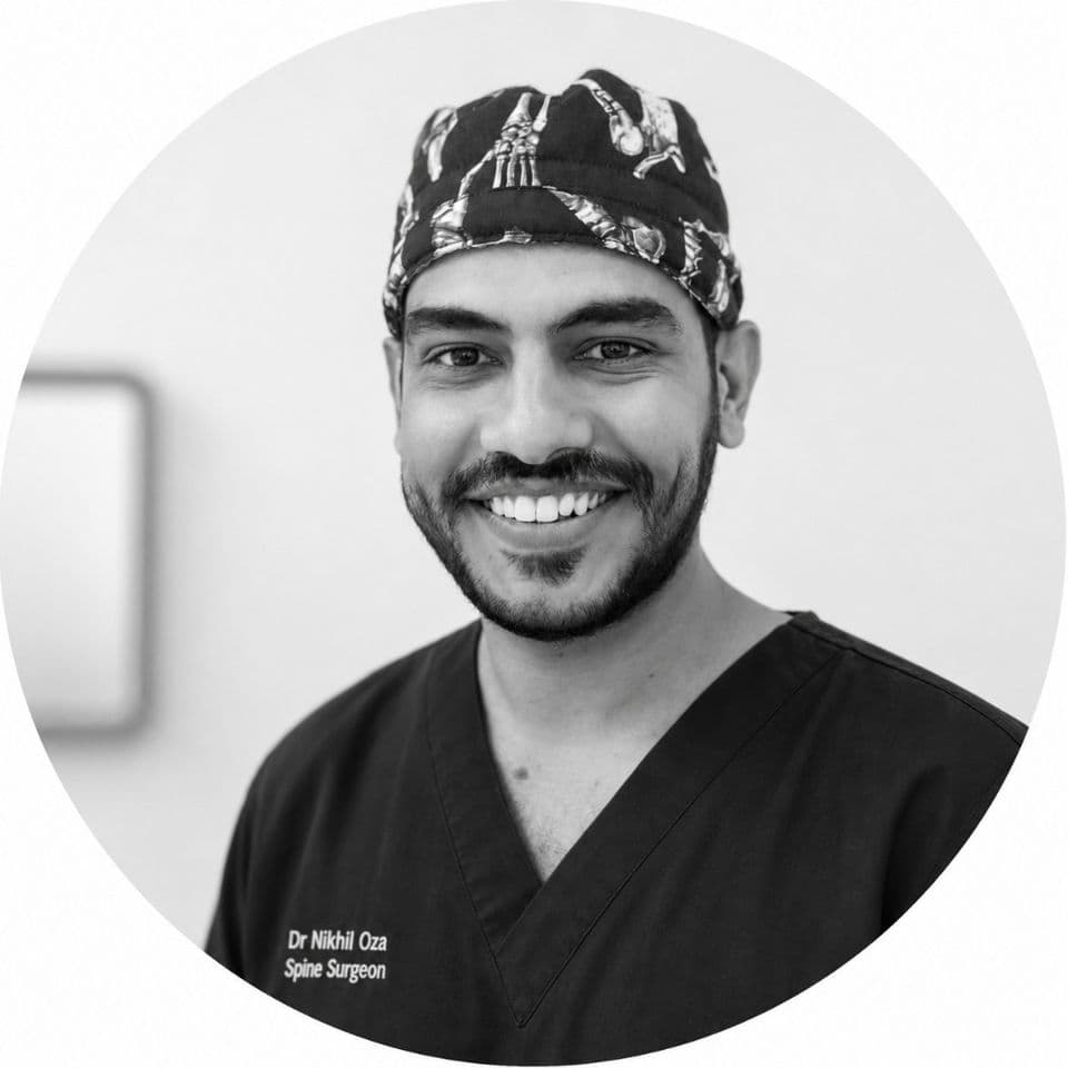 Dr Nikhil Oza, Spine Surgeon, smiling in scrubs and a bone-print surgical cap
